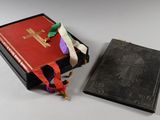 un livre noir à la couverture rouge, orné d'une croix dorée