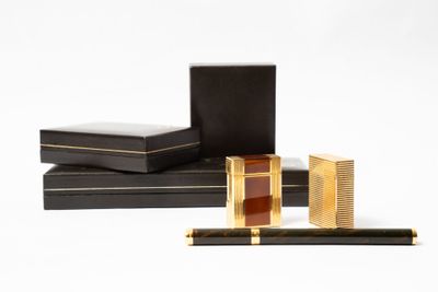 deux boîtes noires ornées de dorures, sur lesquelles est posé un stylo
