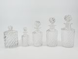 quatre bouteilles en verre munies d'un bouchon, posées sur une surface blanche