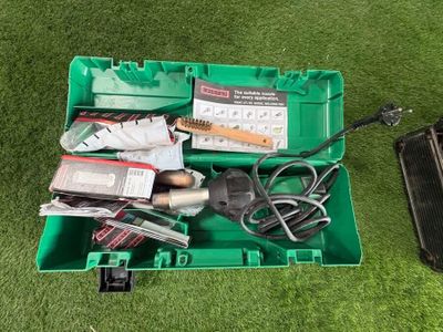 une boîte verte remplie d'outils posée sur l'herbe