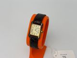 une montre-bracelet orange avec un bracelet noir et une étiquette blanche