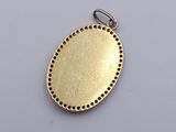 an oval brass pendant with holes in the center on a white surface