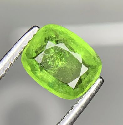 une image montrant un gros plan d'un diamant vert tenu par une paire de pinces