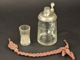 a glass jar with a bird on it next to a glass cup