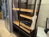 a rack with shelves and a refrigerator in a kitchen