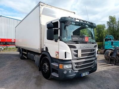 un camion blanc garé sur un parking, avec d'autres camions en arrière-plan
