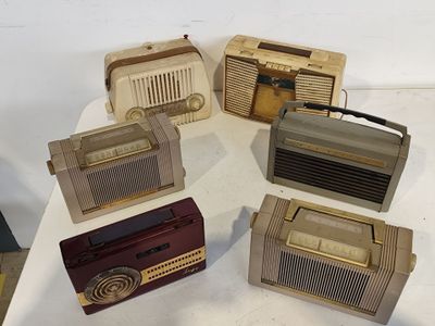 plusieurs radios à l'ancienne posées sur une table blanche