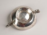 an antique silver plate with a handle on a white surface