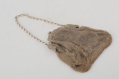 a close up of a purse on a white surface with a chain