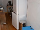 an image of a kitchen with a refrigerator and trash can