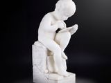 statue en marbre représentant un garçon en train de lire un livre sur fond noir