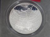 the silver coin is in a plastic case with a red ribbon around it