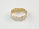 gros plan d'une bague en or et en argent sur une surface blanche