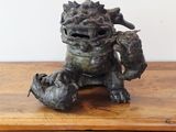 une statue représentant un dragon assis sur une table en bois