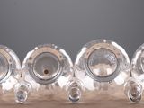 five silver vases sitting on a table with a black background