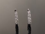 a pair of diamond hoop earrings on a reflective surface