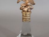 a small glass bottle with a statue of an eagle on it