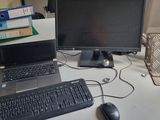 un ordinateur portable posé sur un bureau, à côté d'un écran et d'un clavier