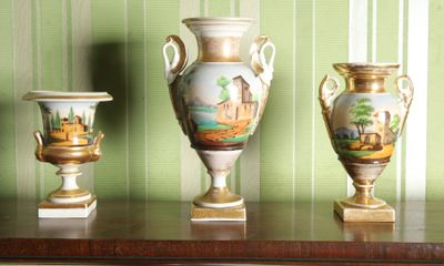 trois vases posés sur une table, avec un mur vert en arrière-plan