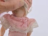 a hand holding a doll with a pink dress on it
