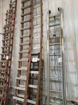 several wooden ladders are lined up against a wall in a warehouse