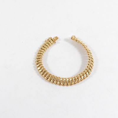 gros plan d'un bracelet en or sur une surface blanche