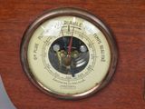 a wooden clock with a barometer on the side of it