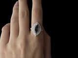 a woman ' s hand holding a ring with a black stone on it