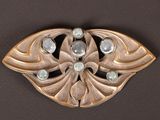 a gold brooch with stones in it on a black surface