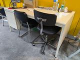 two black chairs sitting at a white desk in a yellow room