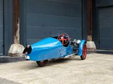a blue race car parked in front of a garage