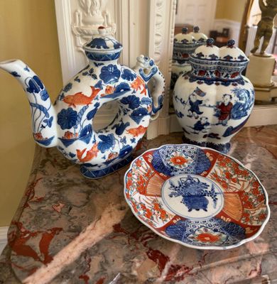 trois théières bleues et blanches et une assiette posées sur une table