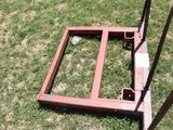 a red frame sitting on the grass next to a pole