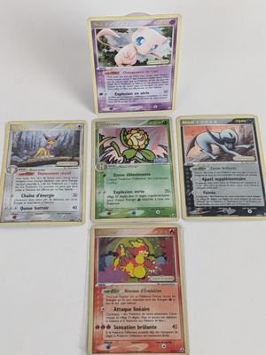 quatre cartes Pokémon posées les unes sur les autres sur une table