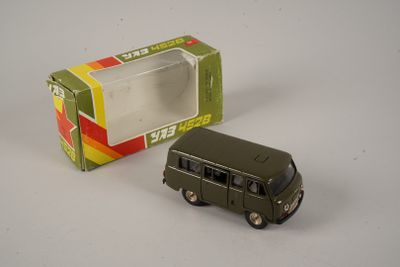 un véhicule militaire miniature posé à côté d'une boîte sur une surface blanche