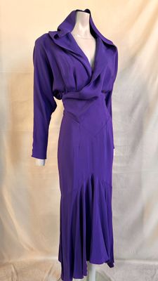 purple dress on a mannequin stand against a white backdrop