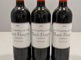 trois bouteilles de vin rouge sont alignées sur une table