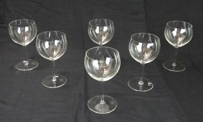 Plusieurs verres à vin vides sont alignés sur une table noire