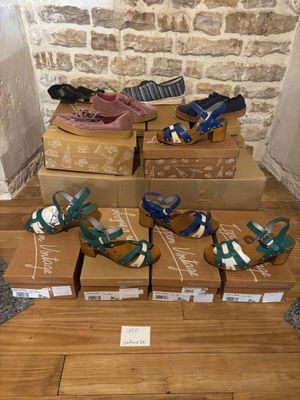 Plusieurs cartons de chaussures sont empilés les uns sur les autres sur un plancher en bois