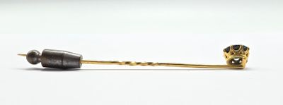 an image of a gold and black pin with a flower on it