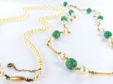 a close up of a necklace with pearls and a green bead