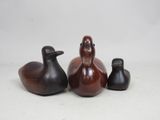 trois petits canards en bois assis les uns à côté des autres sur une surface blanche
