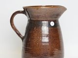 a brown pitcher that is sitting on a white surface