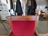 a red chair that is sitting in front of a rack of clothes