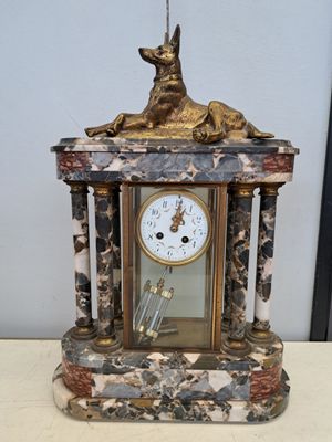 a clock with a dog on top of it sitting on a table