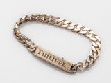 a close up of a gold bracelet with a nameplate on it