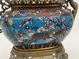 a vase with a bird and flowers on it on a stand