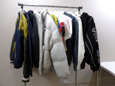 many jackets hanging on a rack in a room