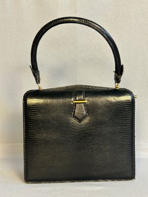 un sac à main noir avec une poignée dorée sur fond blanc