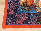 an orange and blue floral design on a black and orange scarf
